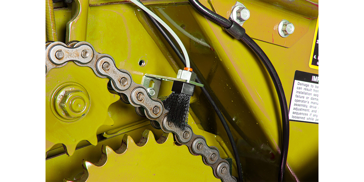 A LubeMinder brush lubricating a chain on a tractor